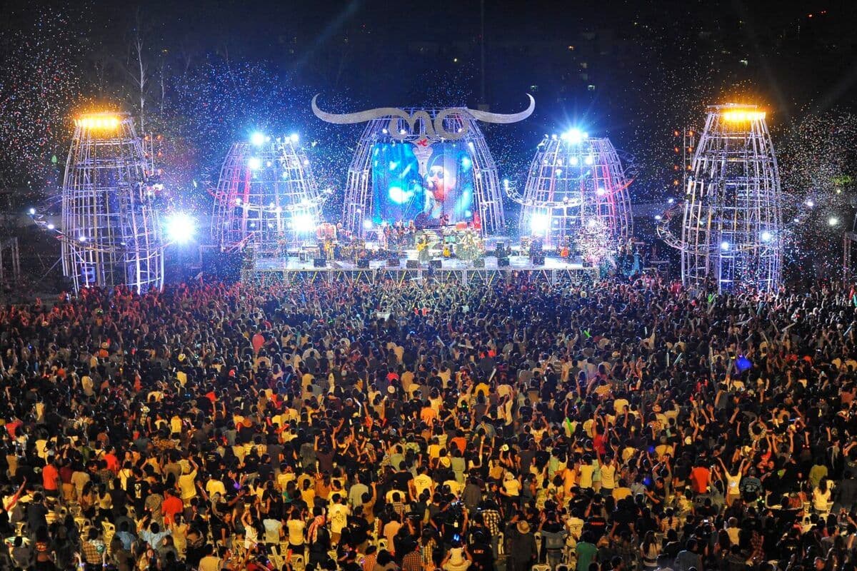 ฝูงชนเต็มลานคอนเสิร์ตกลางแจ้งหน้าเวทีขนาดใหญ่